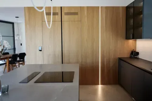 zdjęcie przedstawia zabudowę ścienną, gdzie fornir na ścianie przechodzi w fronty meblowe